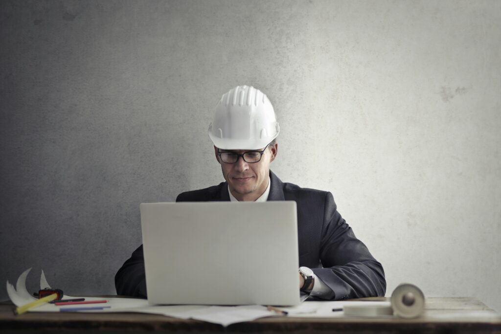 a man wearing a hard hat and looking at a laptop